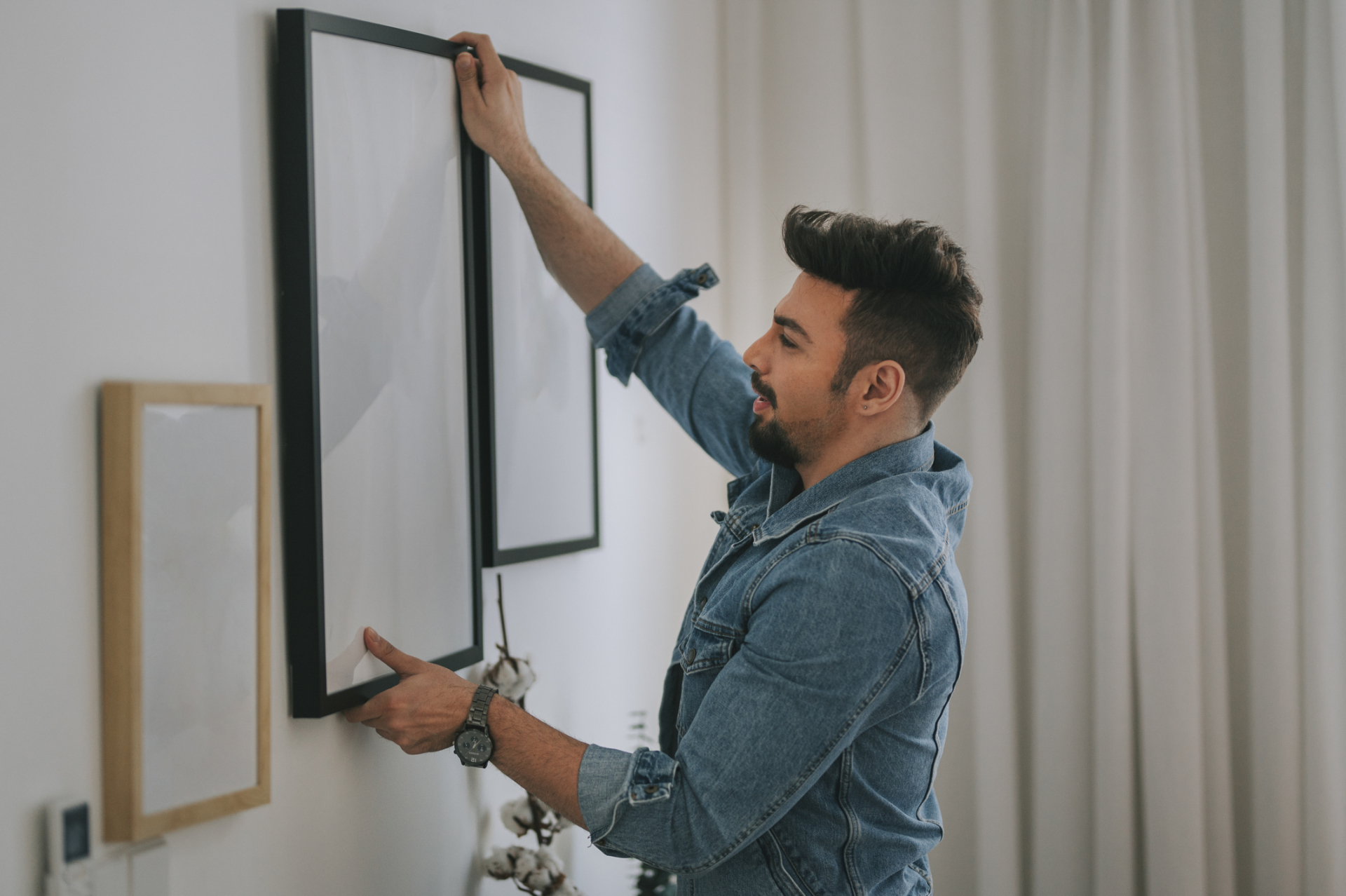 A Smiling Man Installing A Photo Frame